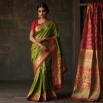 A close-up view of a vibrant Kanjivaram silk saree elegantly draped over a mannequin, showcasing intricate gold zari work and rich mulberry silk with a subtle sheen under soft lighting.