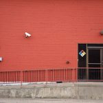 Security camera and rear entrance on a commercial building: Crime Will Strike Almost a Third of UK Businesses This Year