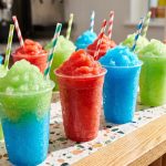 Colourful frozen slush drinks in cups on a retail counter