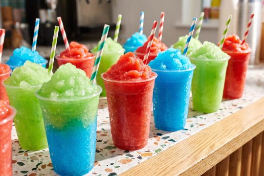 Colourful frozen slush drinks in cups on a retail counter